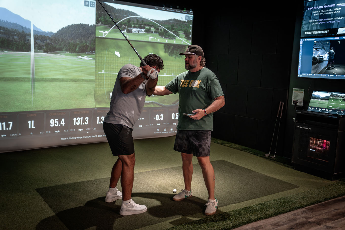 A golfer swinging his club at Tee Box's indoor golf simulator.