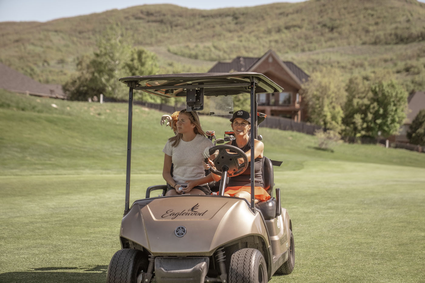 Two Tee Box players in a golf cart.