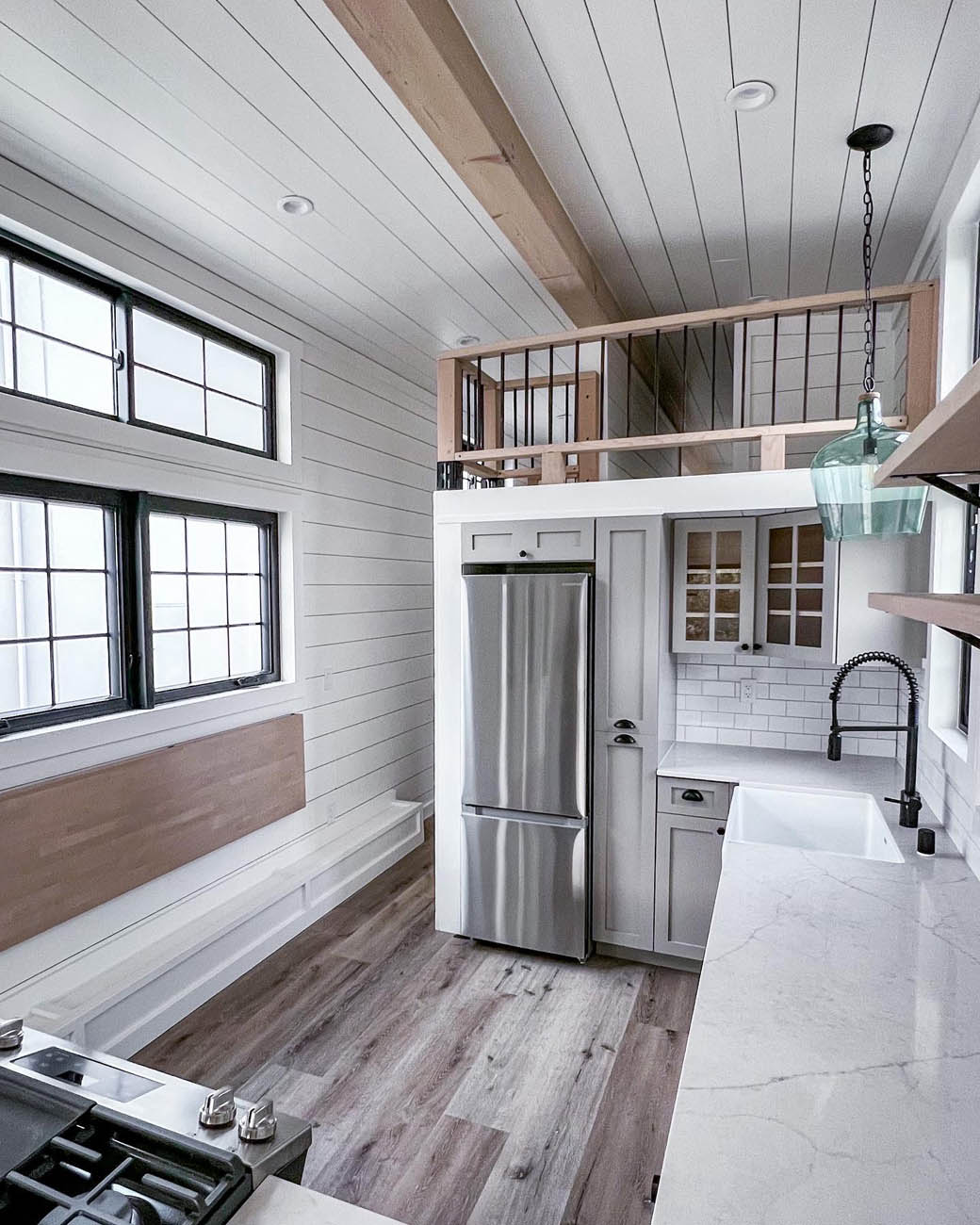 Inside a tiny ADU kitchen with a bedding loft, provided by Anchored Tiny Homes custom small home builder.