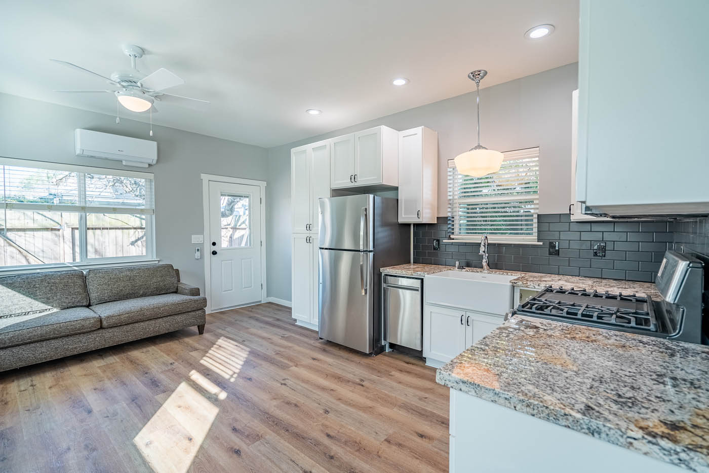 A modern white detached ADUs kitchen with brown marble tops, provided by the best tiny home builders.