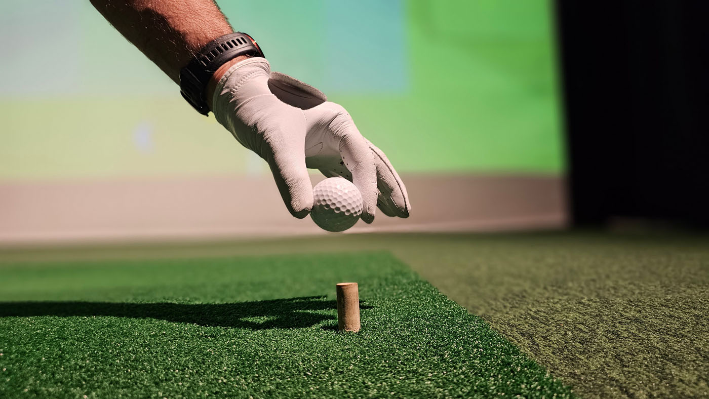 An image of a person teeing up a golf ball at Tee Box.