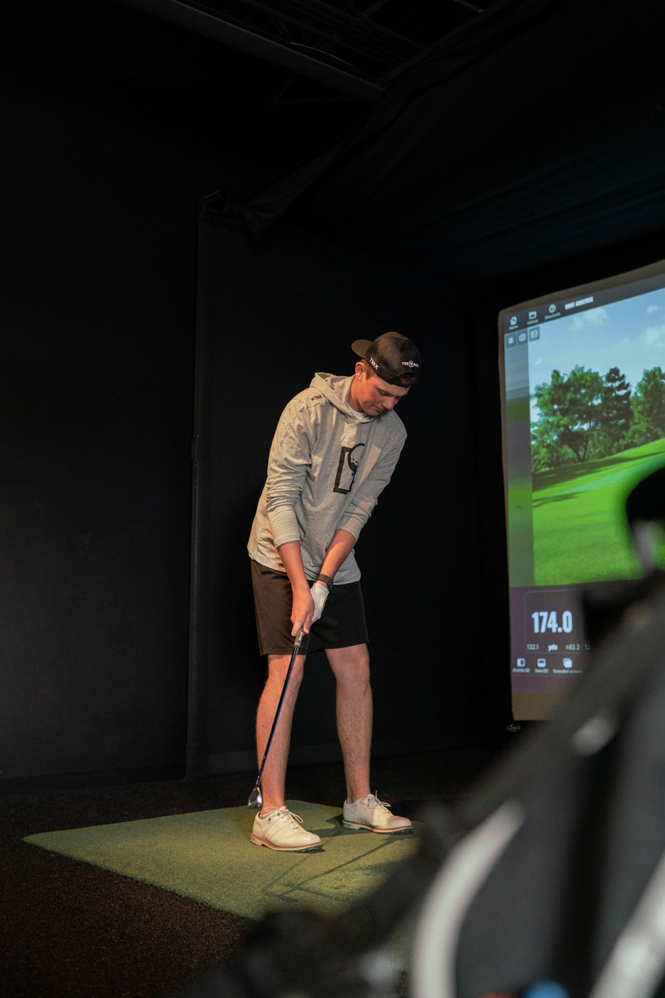 A young golfer training with golf simulator technology at Tee Box.