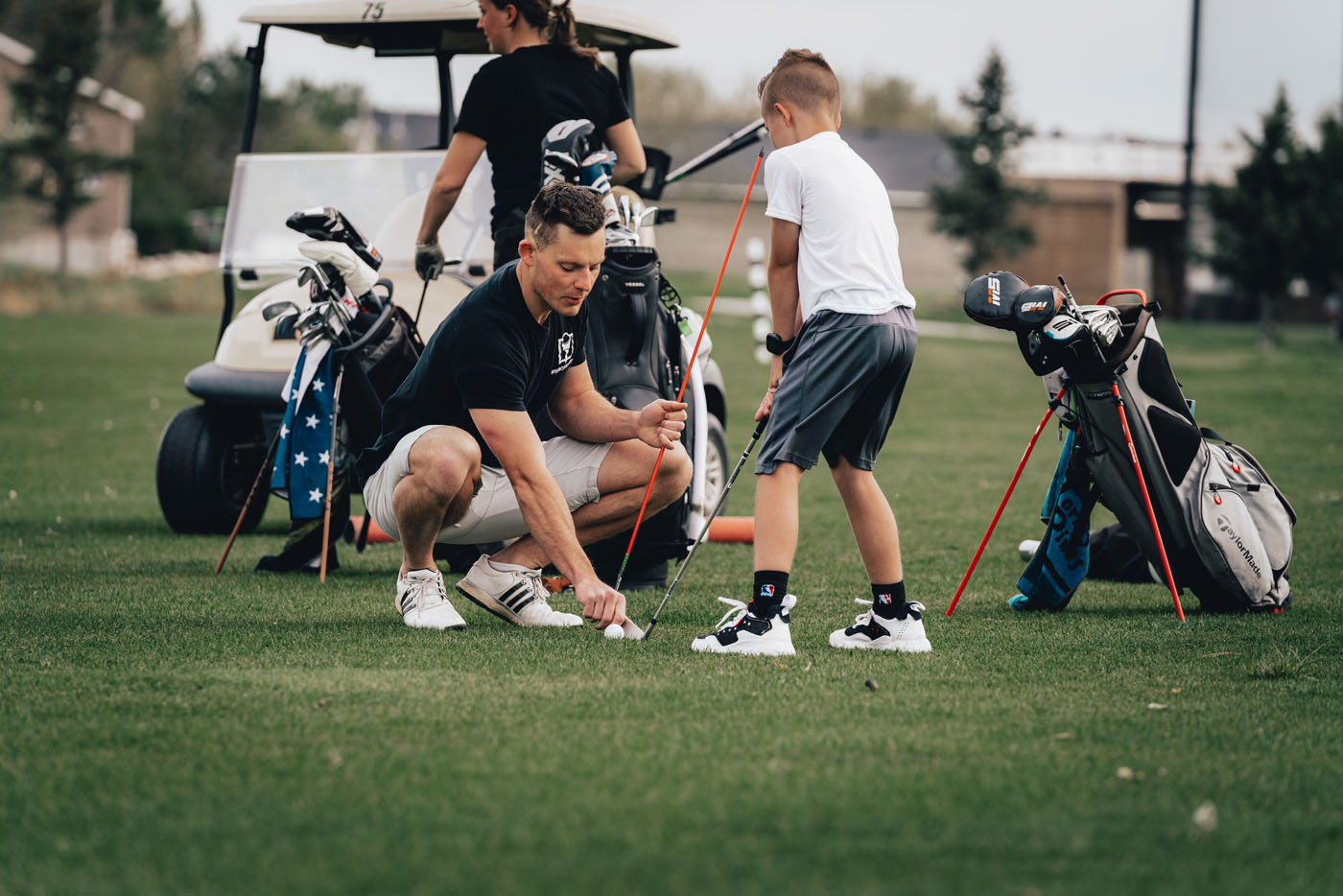 A Tee Box golf instructor in Georgetown, TX helping a younger golfer on our outside course.