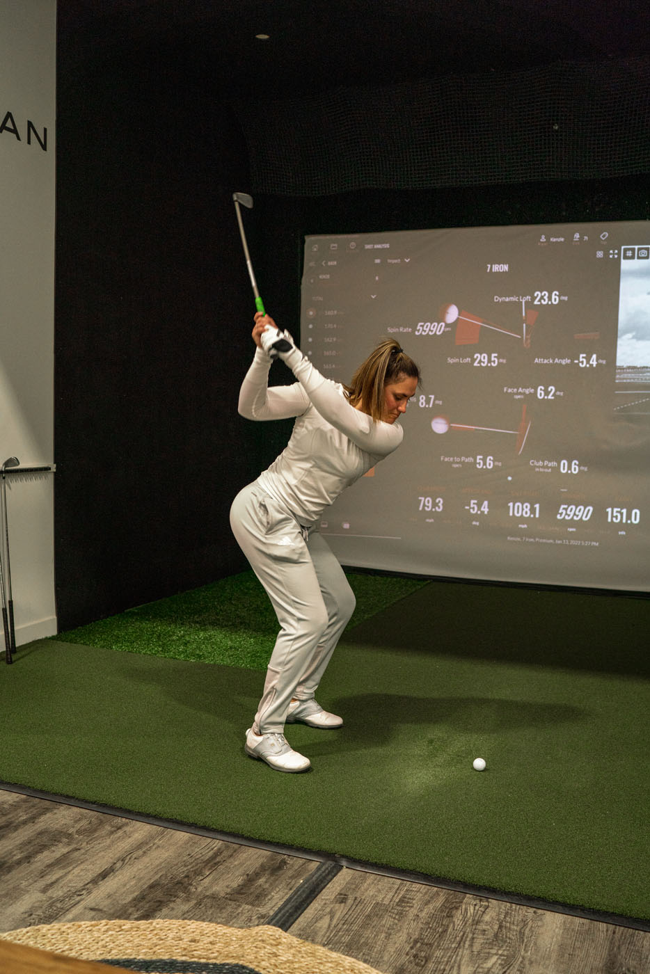 An image of a girl using our McKinney indoor golf practice systems to refine her swing.