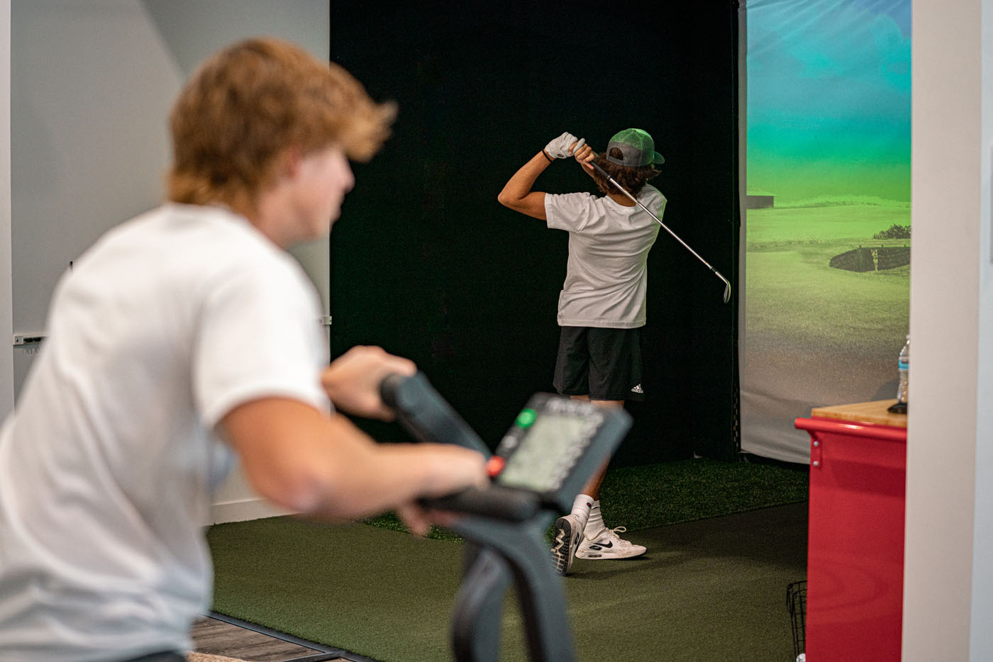 Two Tee Box members working out at our indoor golf simulator in Gilbert, AZ.