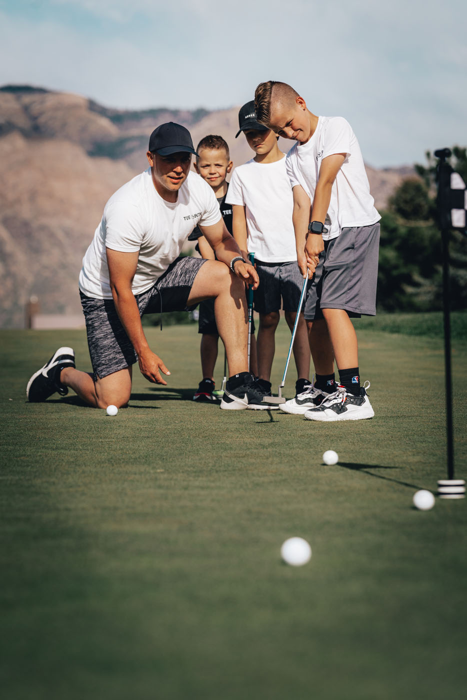 A group of kids playing golf on an outdoor-course at Tee Box Granger.